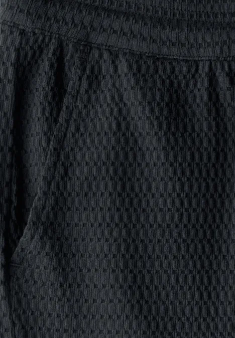 Nahaufnahme einer schwarzen Stoffhose mit Wabenmuster und Tasche.